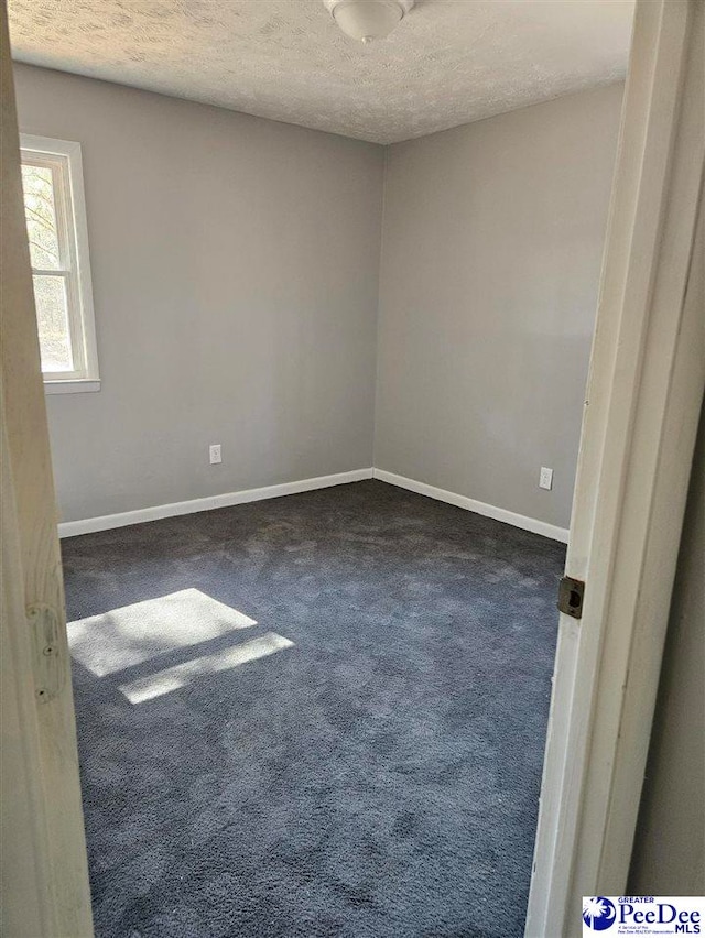 carpeted spare room featuring baseboards and a textured ceiling