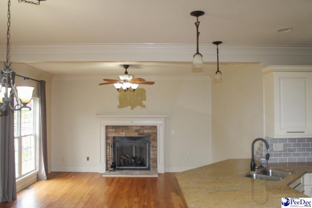 610 Garden Rose Ct, Greer, SC 29651 - unfurnished living room featuring a stone fireplace, crown molding, light wood-style floors, a chandelier, and ceiling fan