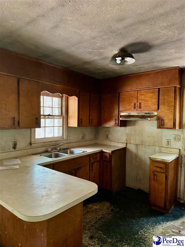 166 Pinestraw Rd, Bennettsville, SC 29512 - kitchen with a peninsula, brown cabinetry, under cabinet range hood, light countertops, and a textured ceiling