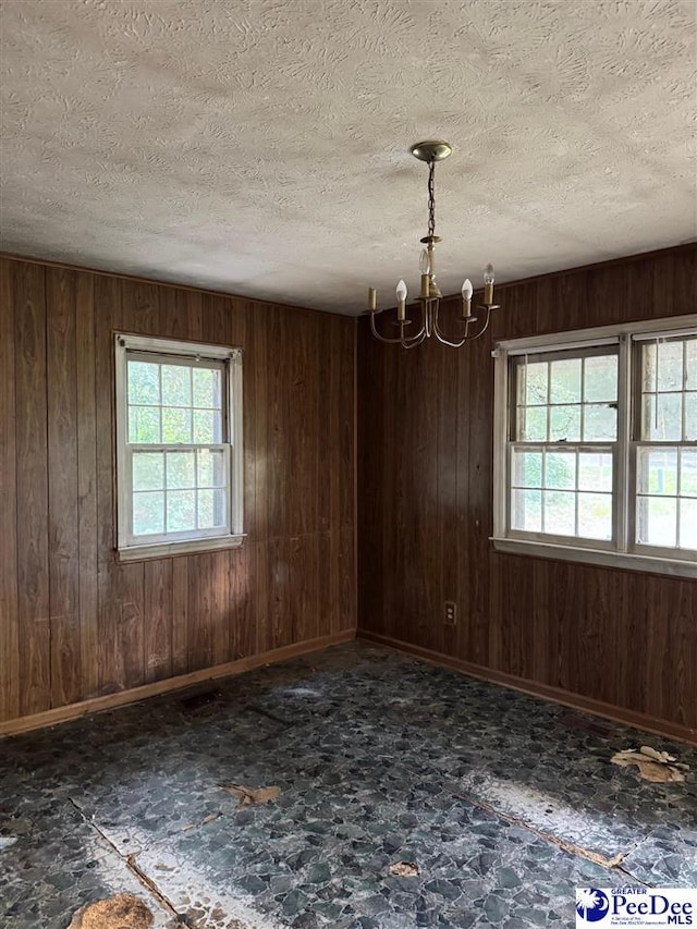 166 Pinestraw Rd, Bennettsville, SC 29512 - spare room featuring healthy amount of natural light, a chandelier, wood walls, and a textured ceiling