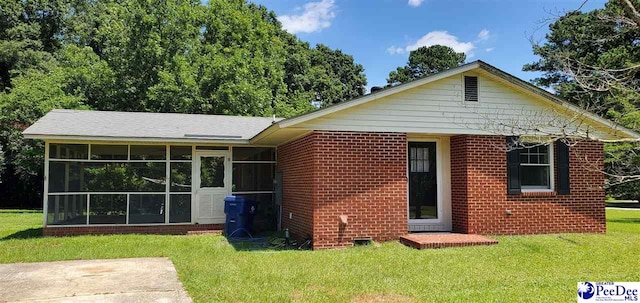 1007 Hamlet Hwy, Bennettsville, SC 29512 - back of property with a sunroom, a lawn, and brick siding