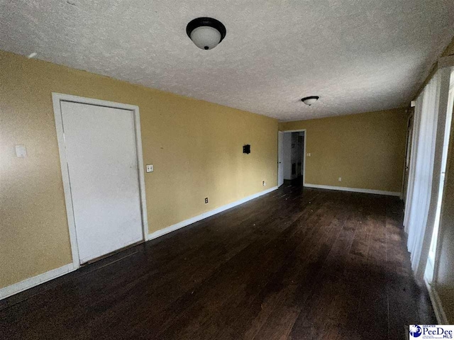 empty room with dark hardwood / wood-style floors and a textured ceiling