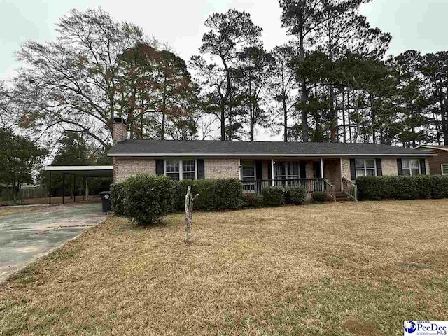 ranch-style home featuring a carport, covered porch, and a front yard