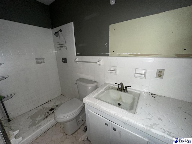 bathroom featuring vanity, toilet, tile walls, and a tile shower