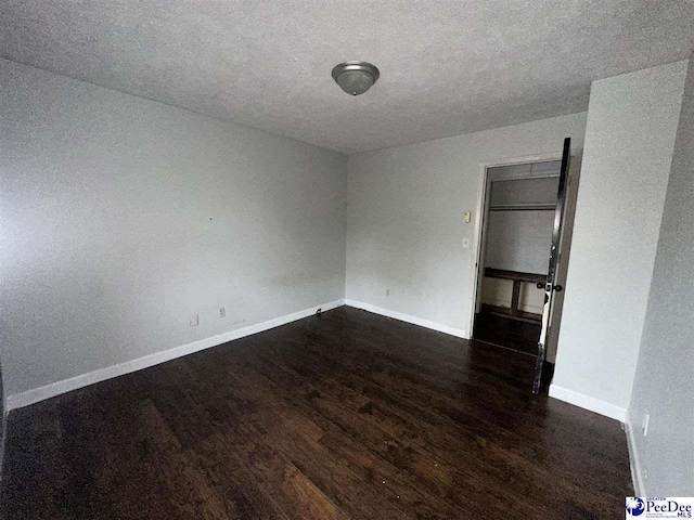 spare room featuring dark wood-type flooring and a textured ceiling