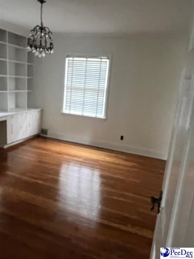 unfurnished room with dark wood-type flooring and a notable chandelier