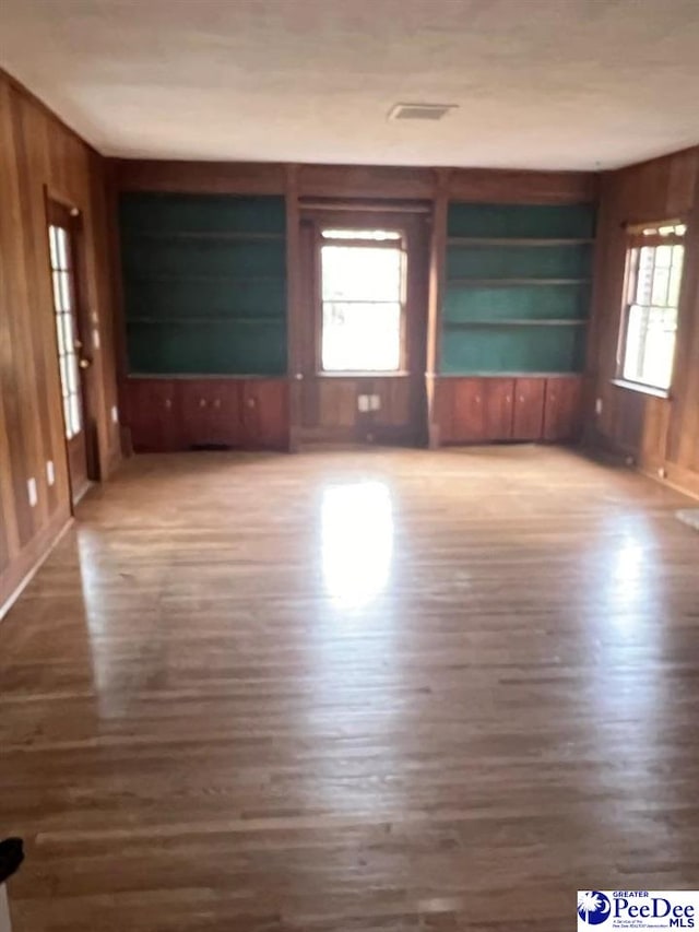 unfurnished living room featuring plenty of natural light and wood walls