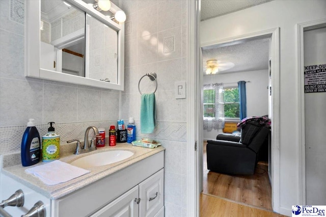1017 Big Swamp Rd, Pamplico, SC 29583 - bathroom with a textured ceiling, wood finished floors, vanity, tile walls, and backsplash