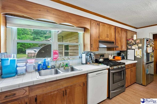 1017 Big Swamp Rd, Pamplico, SC 29583 - kitchen featuring appliances with stainless steel finishes, a sink, under cabinet range hood, crown molding, and brown cabinets