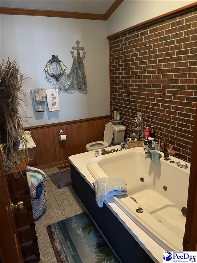 bathroom featuring tile patterned flooring, wooden walls, ornamental molding, a tub to relax in, and toilet