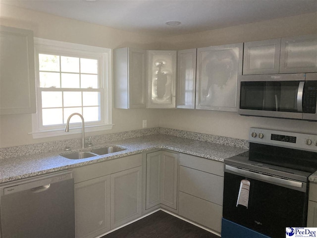 kitchen with white cabinetry, sink, light stone counters, and appliances with stainless steel finishes