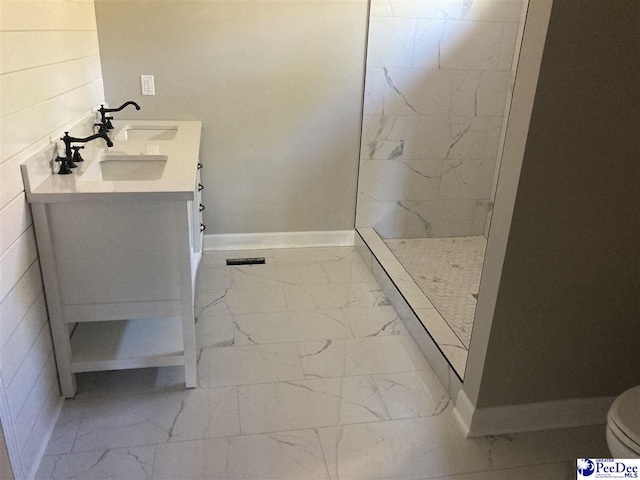 bathroom featuring a tile shower, vanity, and toilet