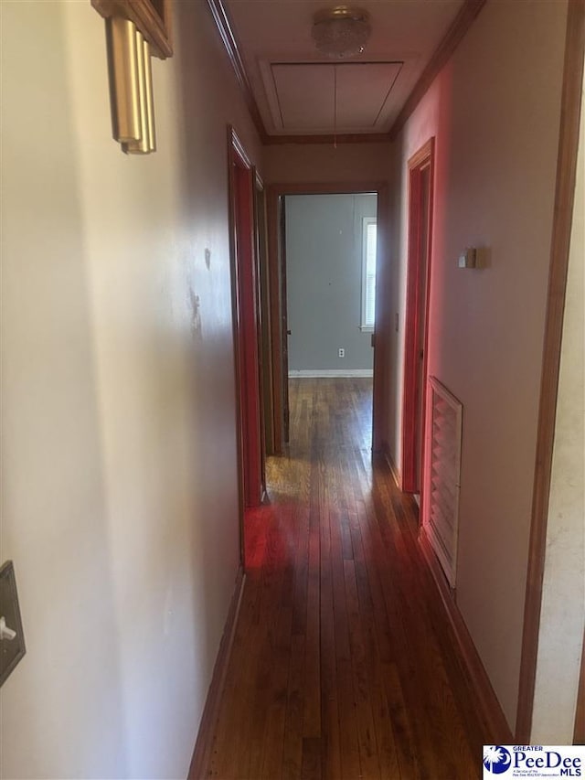 corridor with attic access, baseboards, dark wood finished floors, and ornamental molding