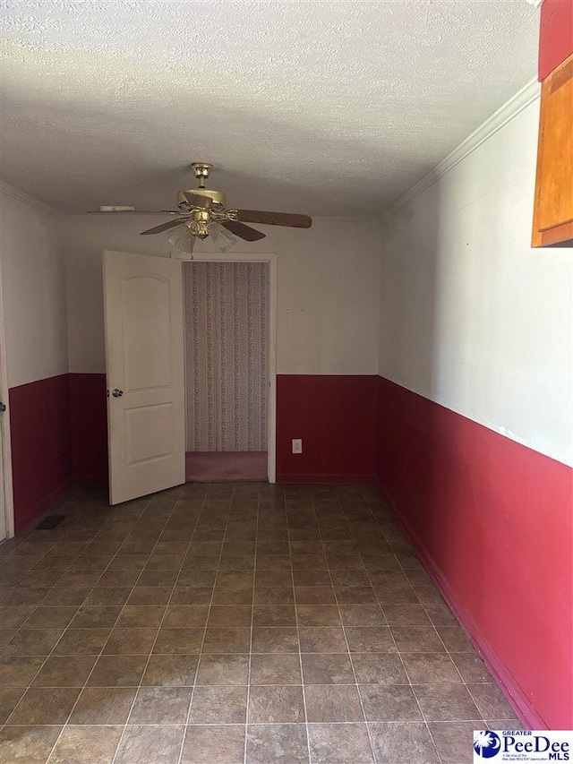 empty room with ceiling fan, ornamental molding, and a textured ceiling