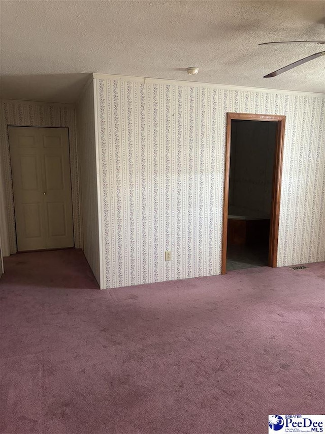 empty room featuring a textured ceiling, carpet floors, and wallpapered walls