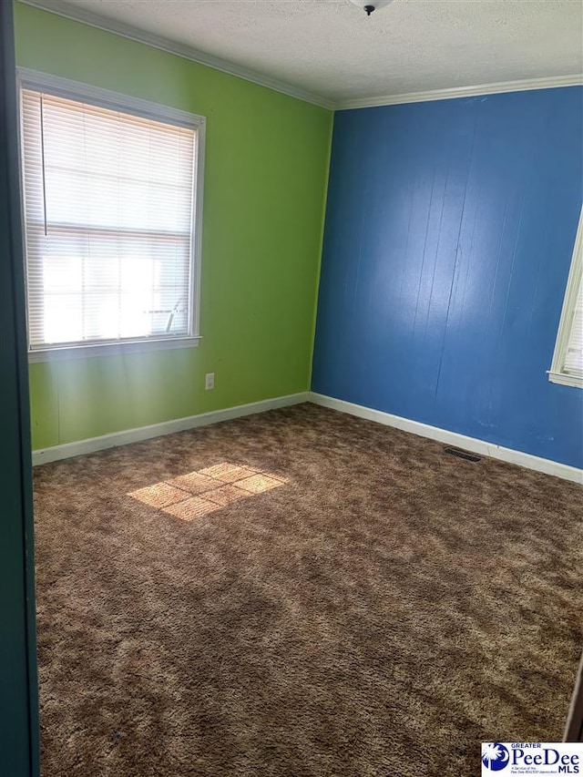 carpeted empty room featuring baseboards, a textured ceiling, visible vents, and crown molding