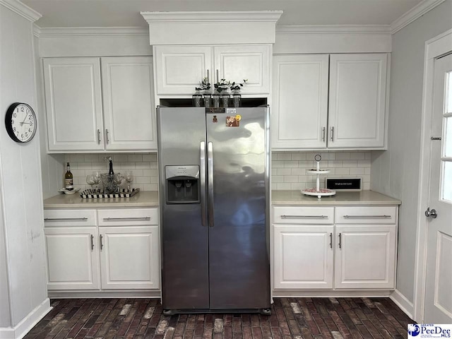 kitchen featuring stainless steel refrigerator with ice dispenser, ornamental molding, decorative backsplash, and white cabinets