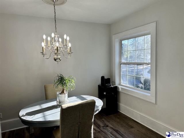 dining room with dark wood-type flooring and an inviting chandelier