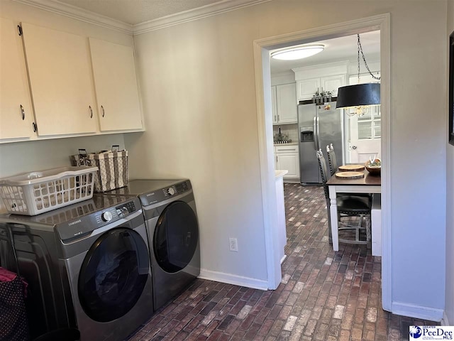 laundry room featuring cabinets, ornamental molding, and washer and clothes dryer
