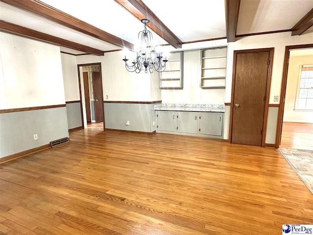 unfurnished dining area featuring beamed ceiling, light wood-type flooring, and a notable chandelier