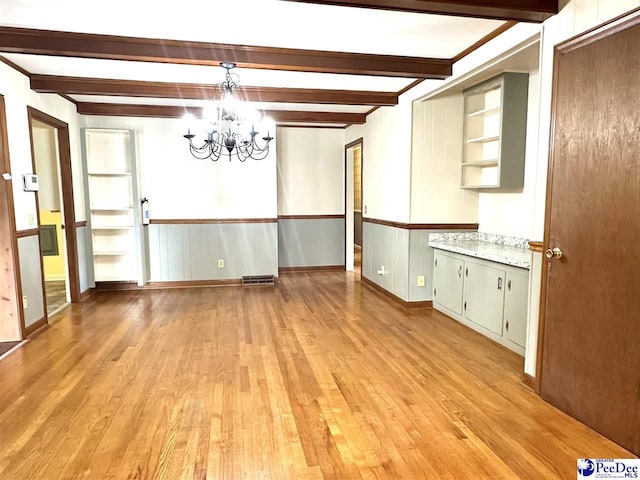 unfurnished dining area featuring beam ceiling, an inviting chandelier, and light hardwood / wood-style floors