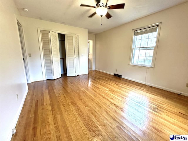 unfurnished bedroom featuring ceiling fan, light hardwood / wood-style floors, and a closet