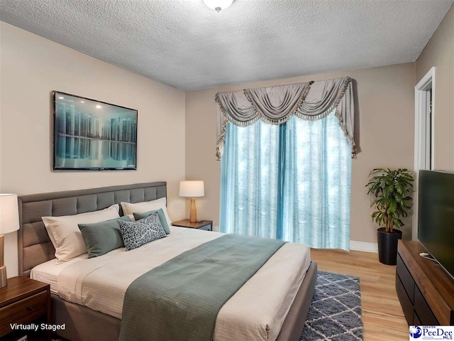 bedroom with light hardwood / wood-style floors and a textured ceiling