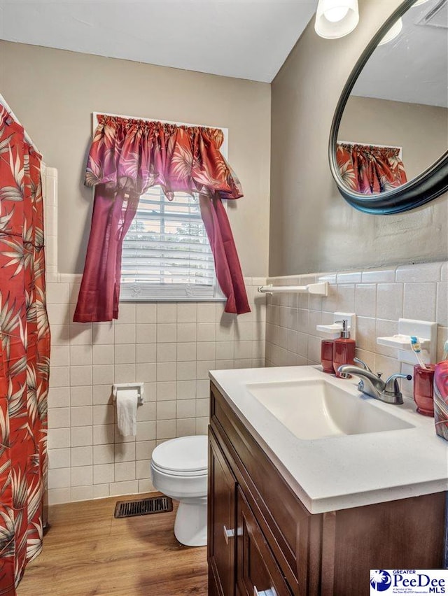 bathroom featuring vanity, wood-type flooring, tile walls, and toilet