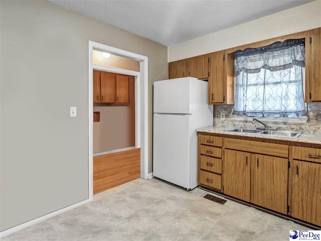 kitchen with tasteful backsplash, white fridge, sink, and a textured ceiling