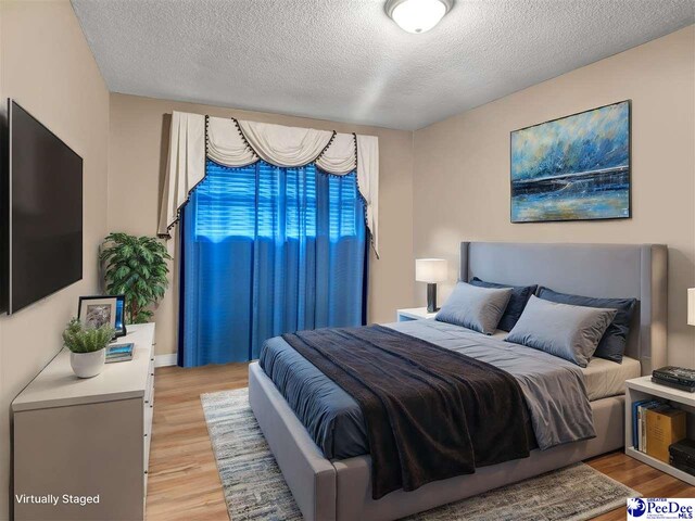 bedroom with a textured ceiling and light wood-type flooring