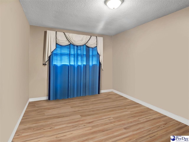 unfurnished room with light hardwood / wood-style flooring and a textured ceiling