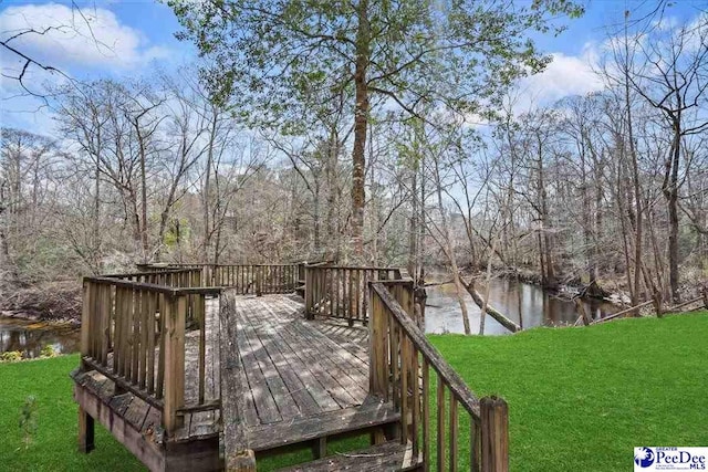 wooden deck featuring a water view, a lawn, and a wooded view