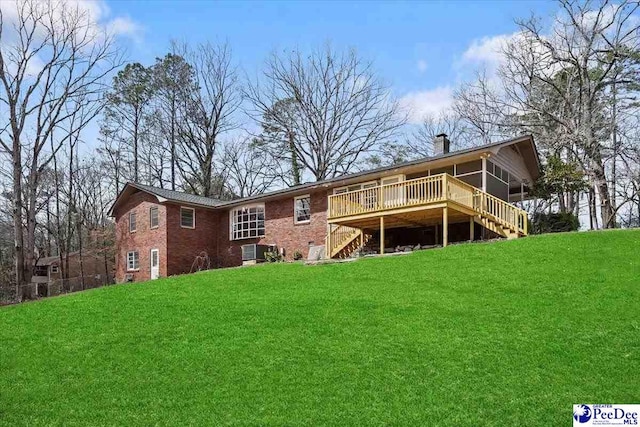 rear view of property featuring brick siding, a yard, a chimney, stairway, and a deck