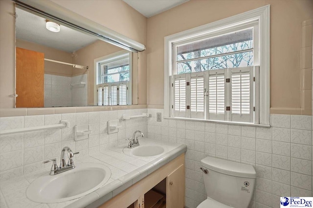 bathroom with double vanity, a sink, toilet, and walk in shower