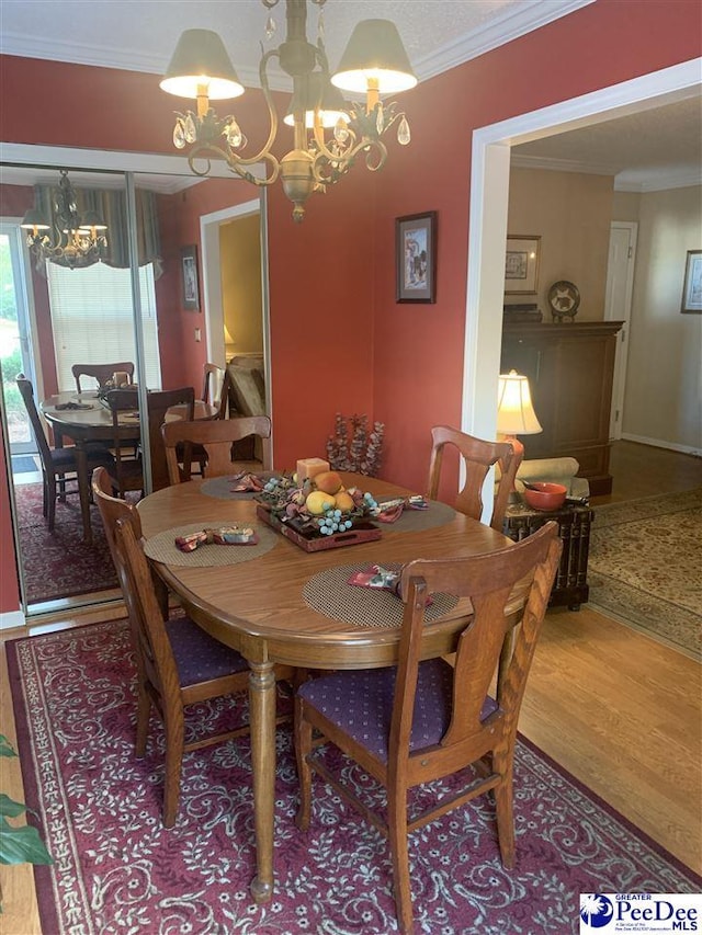 dining room with crown molding, wood-type flooring, and a chandelier