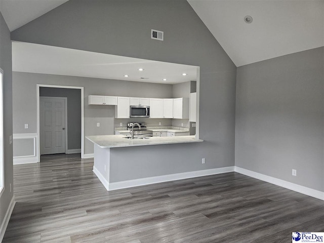 kitchen with sink, white cabinetry, stainless steel appliances, dark hardwood / wood-style floors, and kitchen peninsula