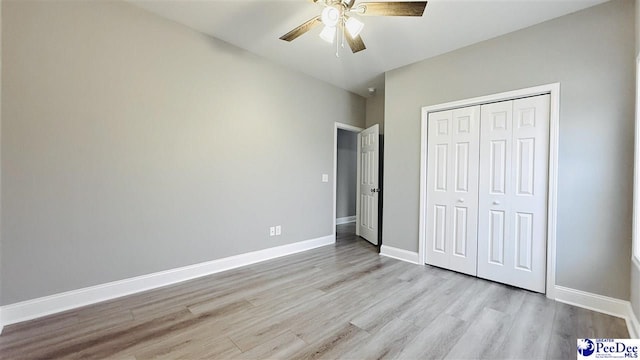 unfurnished bedroom featuring baseboards, a ceiling fan, wood finished floors, and a closet