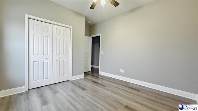 unfurnished bedroom featuring baseboards, wood finished floors, a closet, and ceiling fan