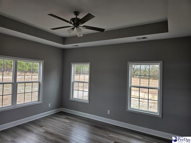 empty room featuring ceiling fan, dark hardwood / wood-style flooring, and a tray ceiling