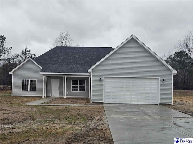 view of front of house with an attached garage, concrete driveway, and roof with shingles