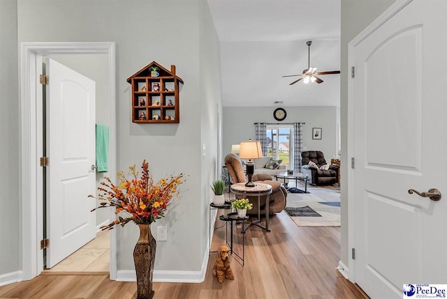 hallway with vaulted ceiling and light wood-type flooring