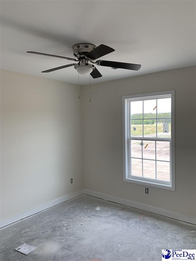 spare room featuring baseboards, ceiling fan, and concrete floors