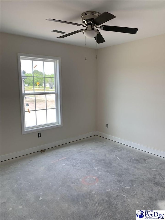 spare room featuring baseboards, ceiling fan, and unfinished concrete flooring