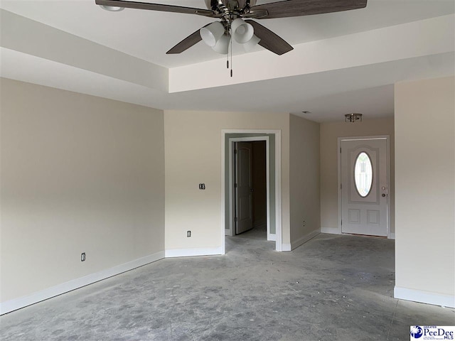 interior space with unfinished concrete floors, ceiling fan, and baseboards