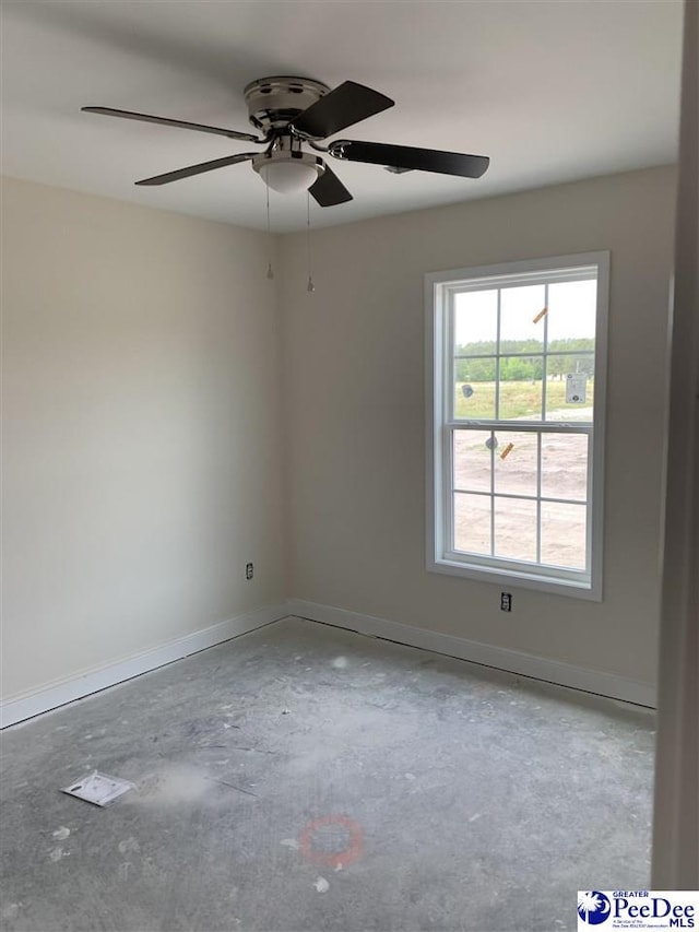 spare room with baseboards, ceiling fan, and unfinished concrete floors