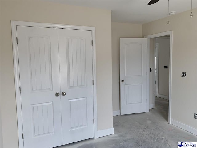 unfurnished bedroom with baseboards, ceiling fan, concrete floors, and a closet