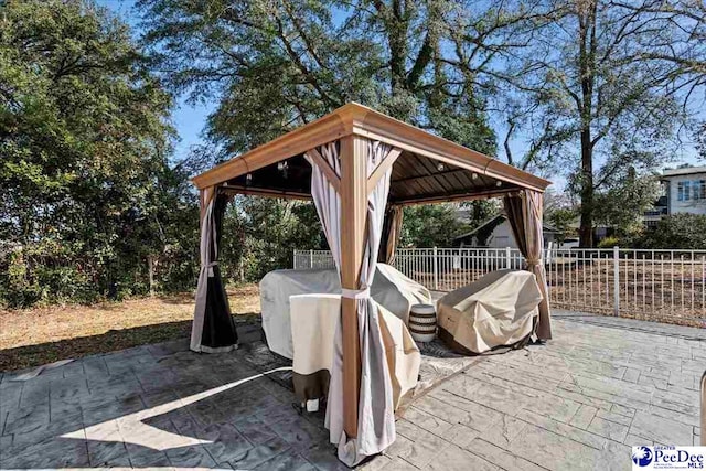 view of patio / terrace featuring a grill, fence, and a gazebo