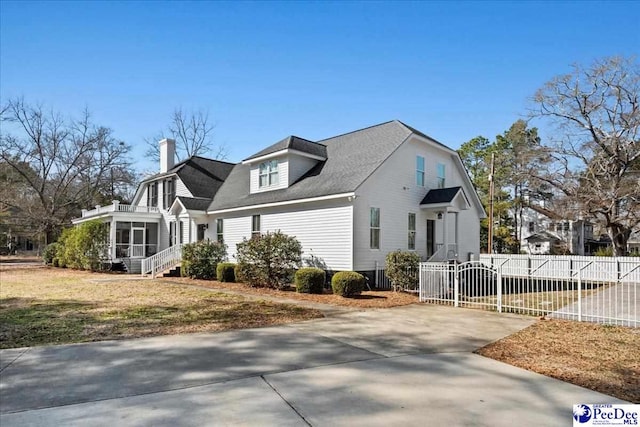 view of side of home featuring a yard, a chimney, a sunroom, a gate, and fence