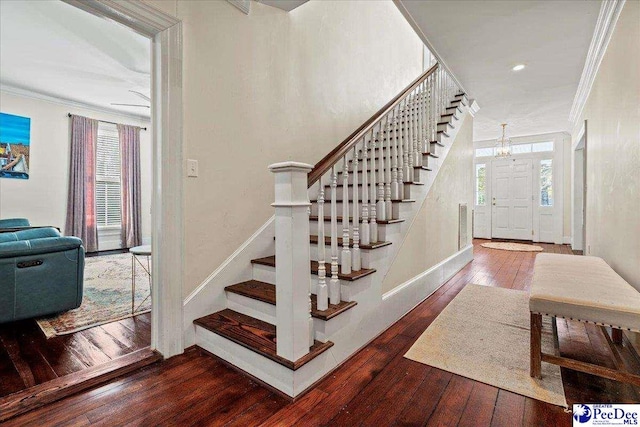 staircase with visible vents, crown molding, and wood finished floors