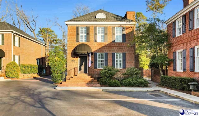 view of front of house with uncovered parking and brick siding